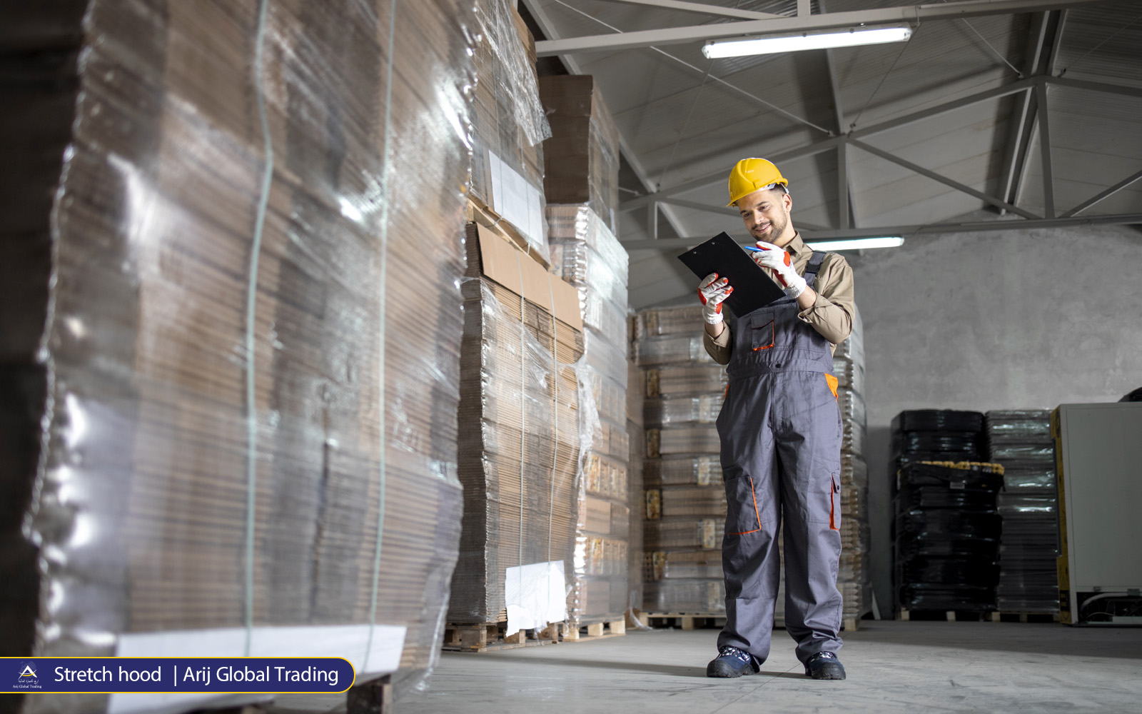 03 Stretch hood Arij-Global-Trading Arij co worker in safety gear inspects LDPE-wrapped pallets in modern warehouse
