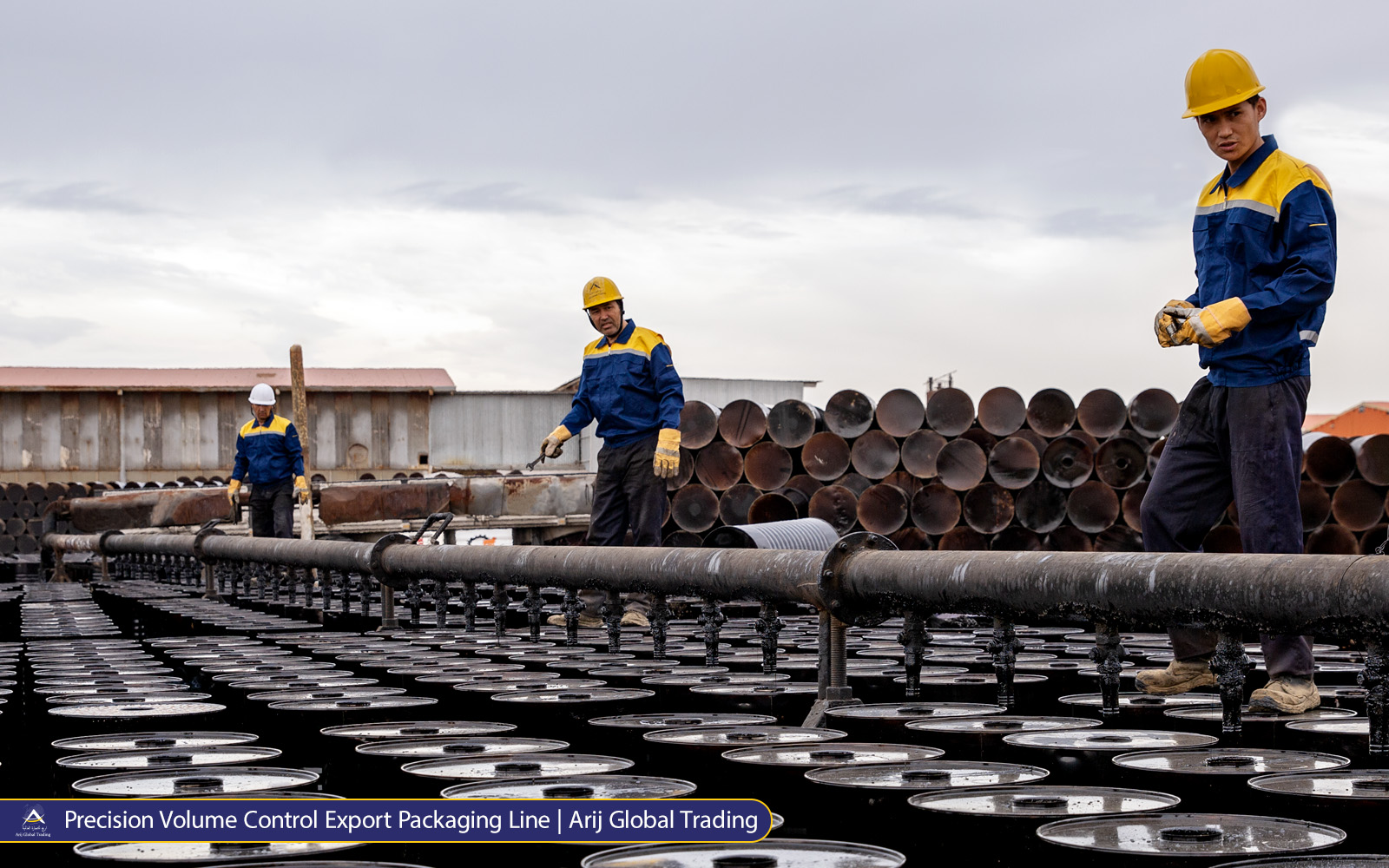 A facility operator carefully adjusts a heavy-duty pipeline valve during the mass filling of industrial steel drums, ensuring precise cargo loading for Arij Global Trading clients.