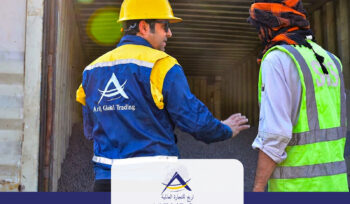 Quality inspection of Direct Reduced Iron (DRI) inside a shipping container by an Arij Global Trading representative wearing safety gear and discussing the cargo with an SGS inspector before export.