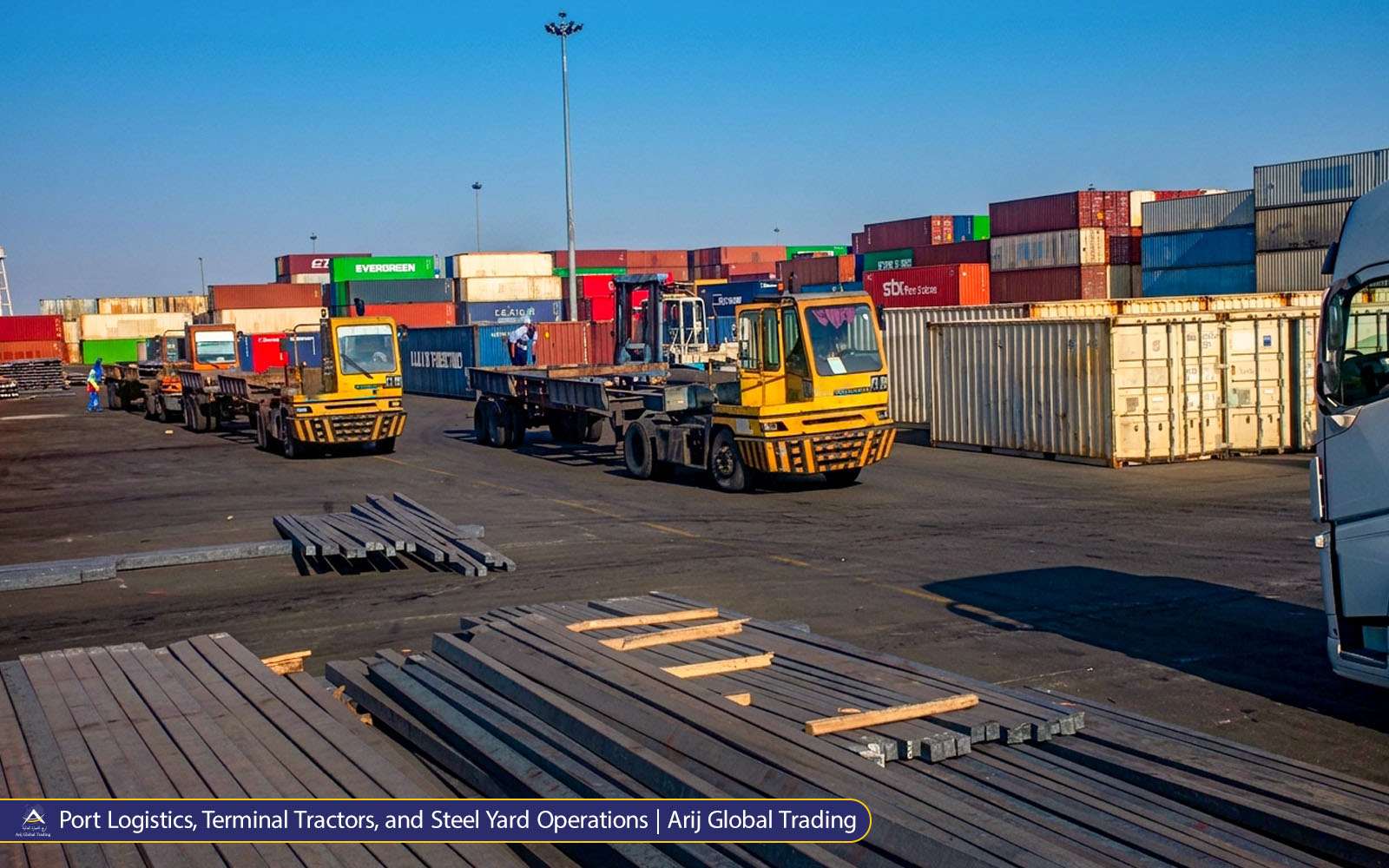 Port Logistics, Terminal Tractors, and Steel Yard Operations | Arij Global Trading Yellow terminal tractors hauling flatbeds through a shipping container yard with stacked steel billets in the foreground. Arij Global Trading port logistics and steel handling operations.