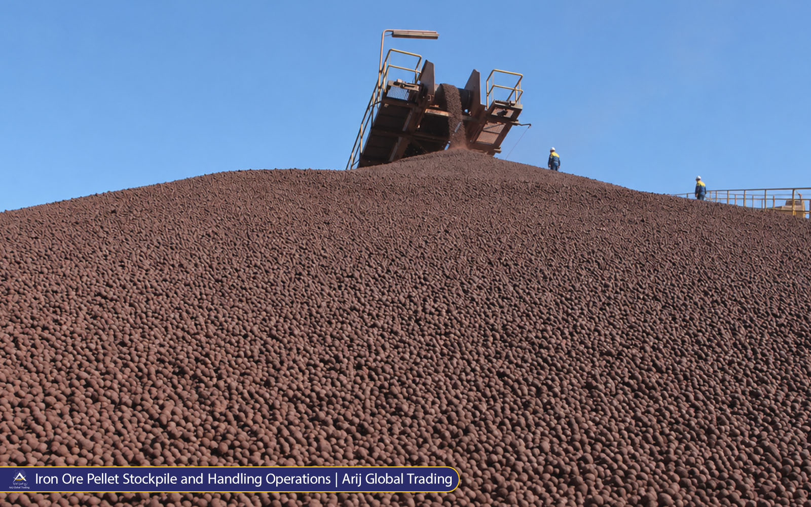 Iron Ore Pellet Stockpile and Handling Operations | Arij Global Trading Large stockpile of reddish-brown iron ore pellets at an industrial handling facility, with conveying equipment and distant workers monitoring operations.
